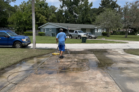 man pressure washing driveway